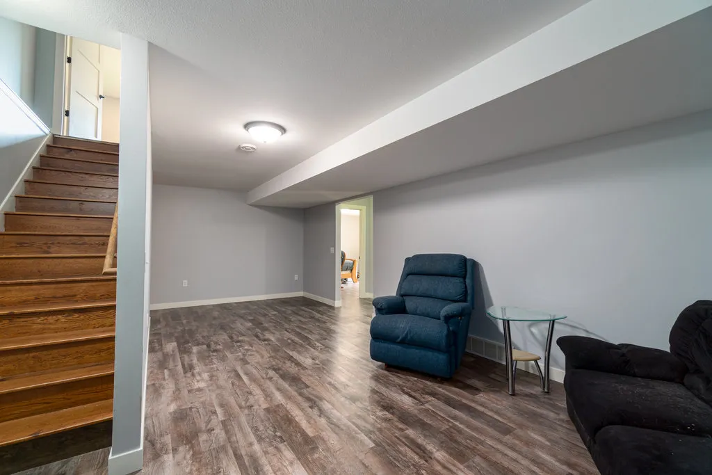 Basement living area with hardwood stairs and vinyl plank