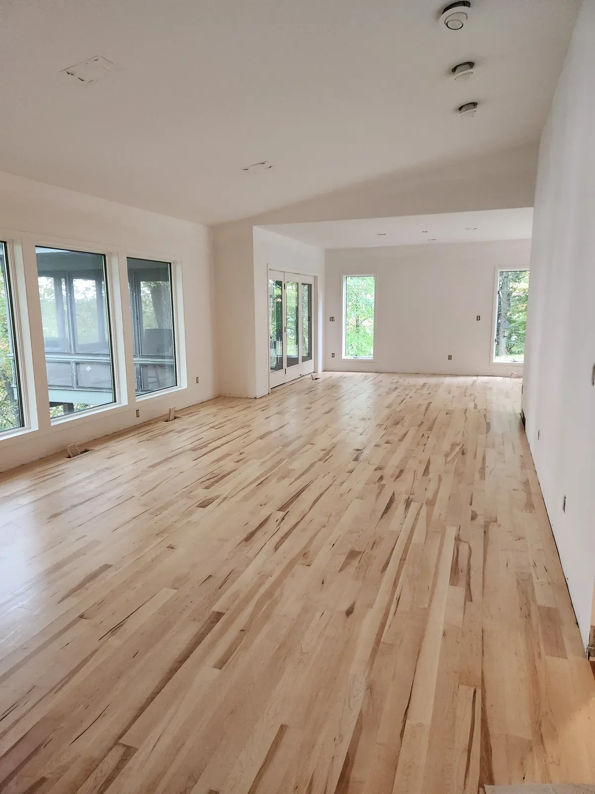 Open-plan room with new maple hardwood floors and large windows