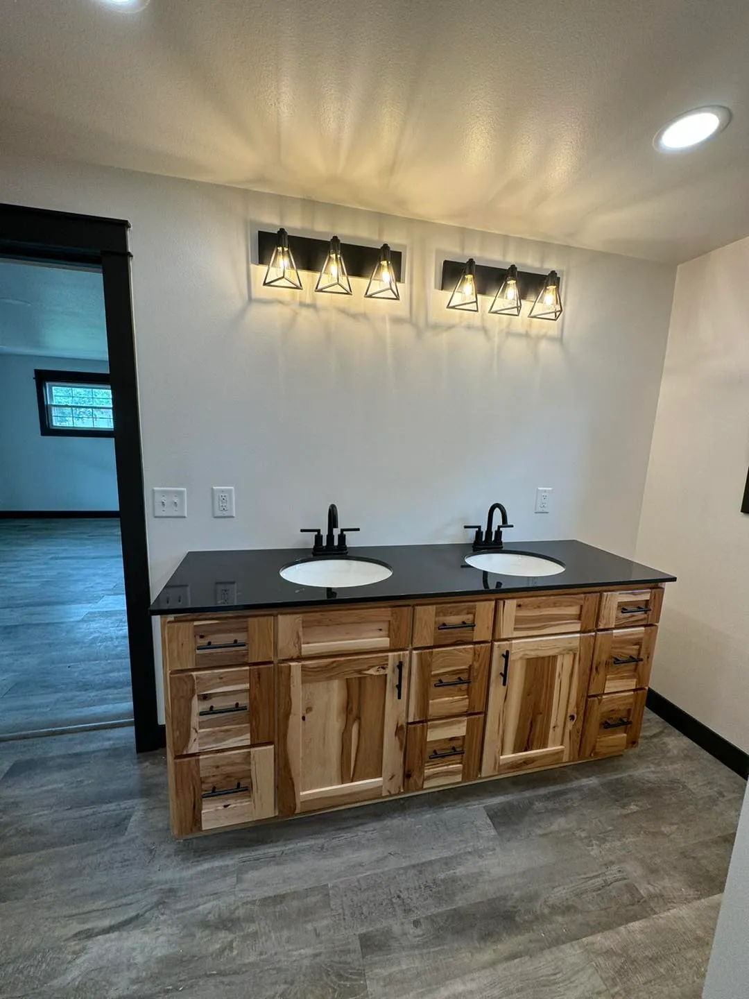 Hickory vanity bathroom with double sinks and black countertop