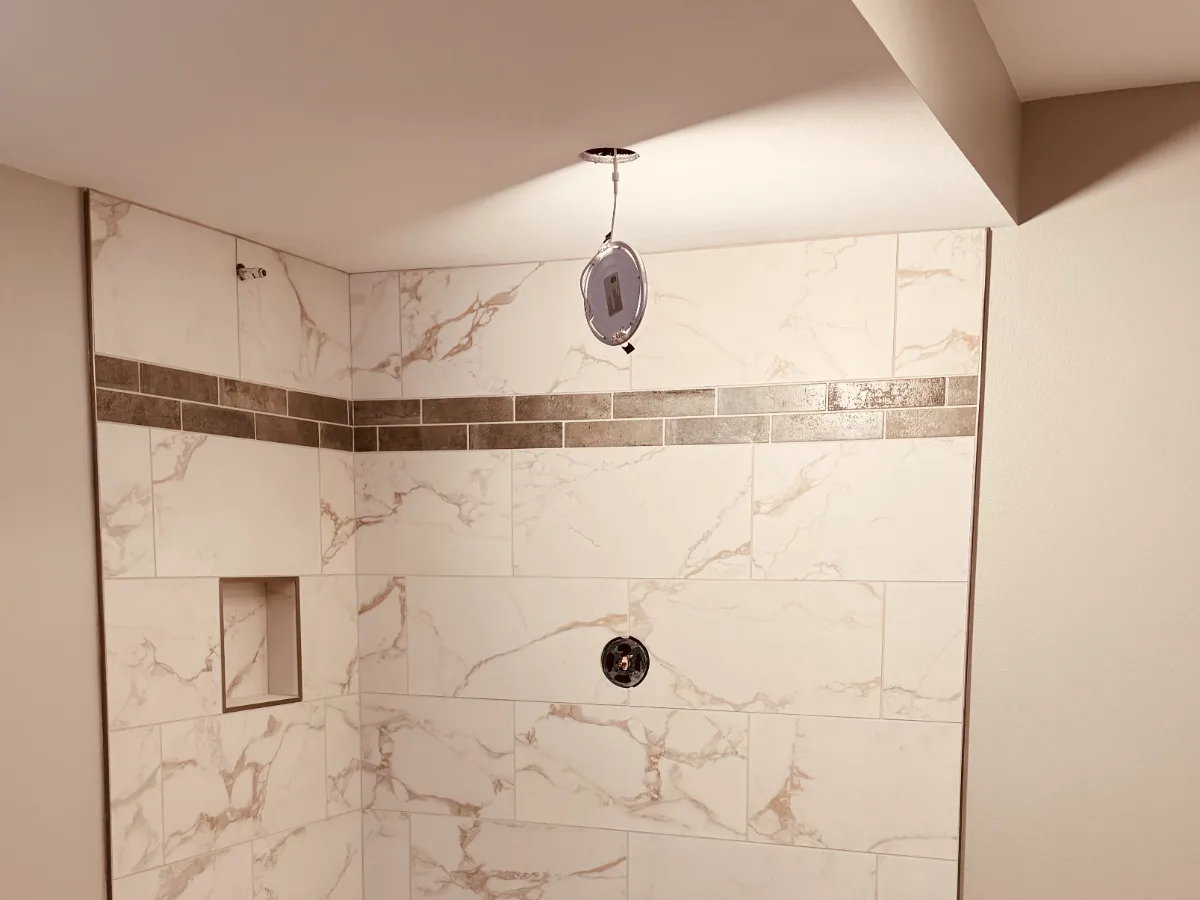 Marble-look shower tile and accent band during installation